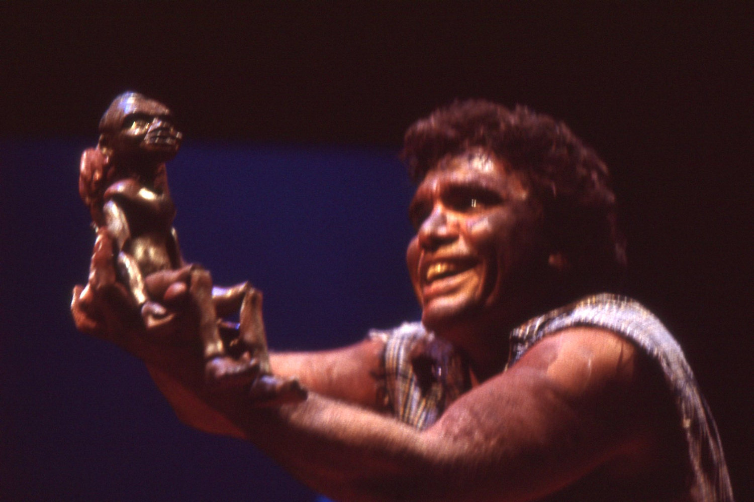 Aboriginal actor with joyful expression holding up rod puppet Aboriginal boy 